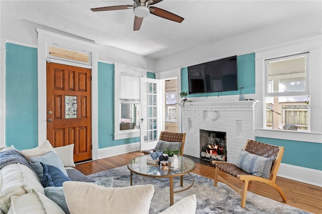 living room with ceiling fan, a fireplace, and hardwood / wood-style flooring