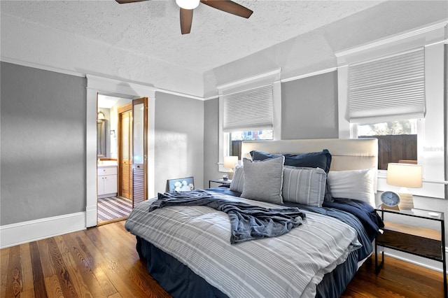 bedroom with a textured ceiling, ceiling fan, dark wood-type flooring, and connected bathroom