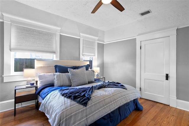 bedroom with hardwood / wood-style flooring, ceiling fan, and a textured ceiling