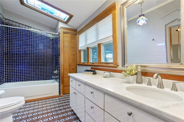 full bathroom with vaulted ceiling with skylight, vanity, toilet, and tiled shower / bath combo