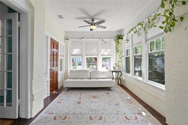 unfurnished sunroom featuring ceiling fan and a healthy amount of sunlight