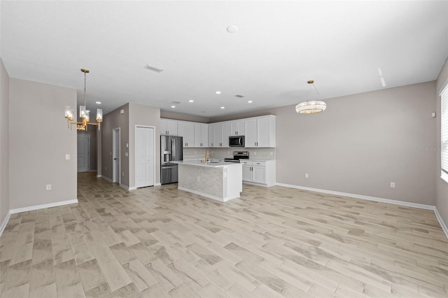 kitchen with decorative light fixtures, a center island with sink, light hardwood / wood-style flooring, white cabinetry, and stainless steel appliances