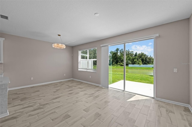 unfurnished room featuring a textured ceiling, plenty of natural light, and light hardwood / wood-style floors