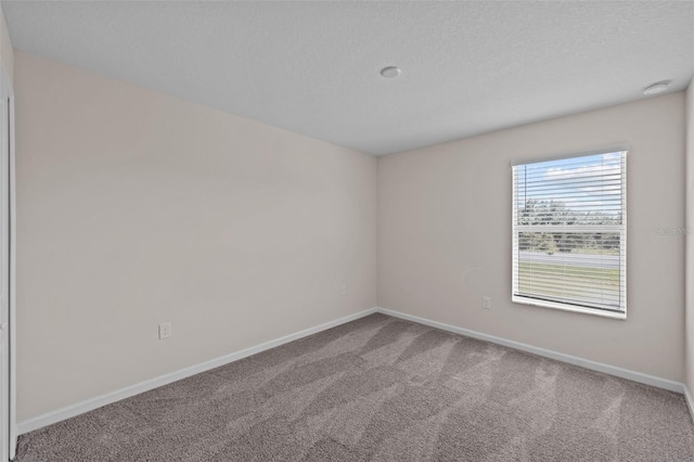 carpeted empty room featuring a textured ceiling