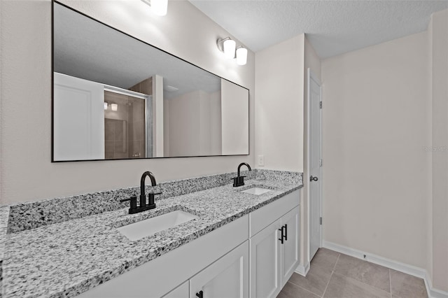 bathroom featuring tile patterned flooring, a textured ceiling, a shower with door, and vanity