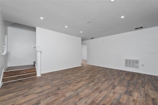 empty room with a textured ceiling and dark hardwood / wood-style floors