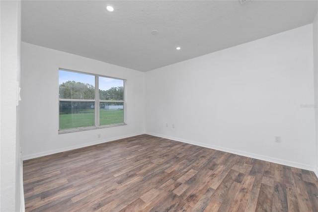 spare room featuring a textured ceiling and dark hardwood / wood-style flooring