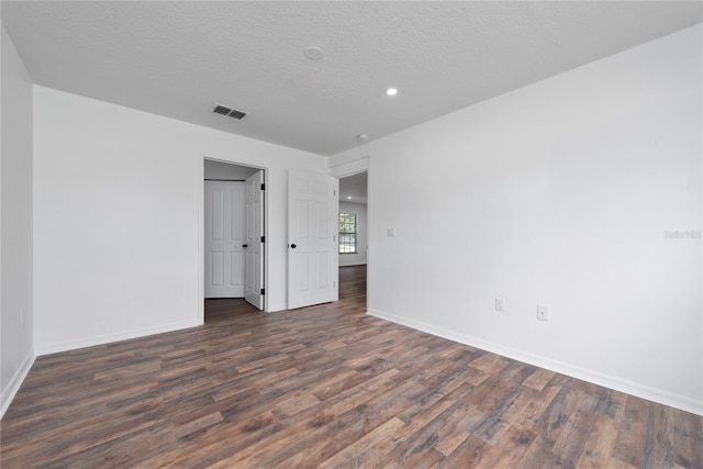 spare room featuring a textured ceiling and dark hardwood / wood-style flooring