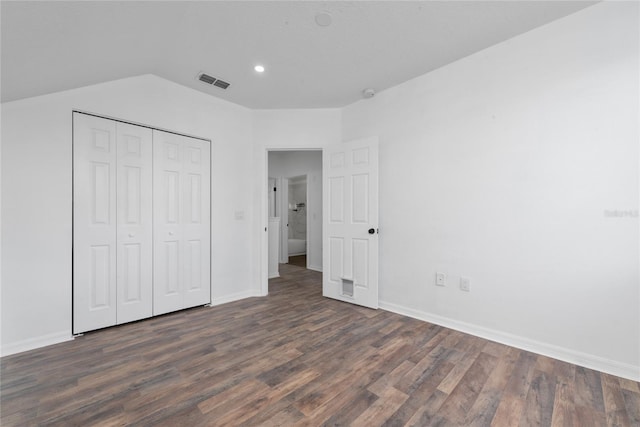 unfurnished bedroom with vaulted ceiling, dark hardwood / wood-style floors, and a closet