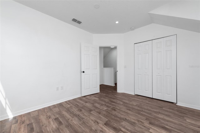 unfurnished bedroom featuring lofted ceiling, a closet, and dark hardwood / wood-style flooring