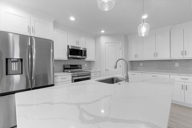 kitchen featuring white cabinets, stainless steel appliances, light wood-type flooring, decorative light fixtures, and sink