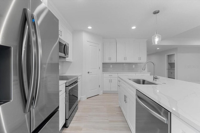 kitchen featuring appliances with stainless steel finishes, hanging light fixtures, tasteful backsplash, white cabinets, and sink