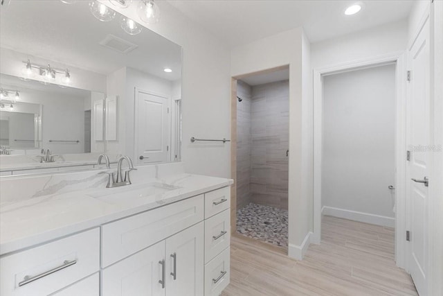 bathroom featuring vanity, hardwood / wood-style flooring, and tiled shower