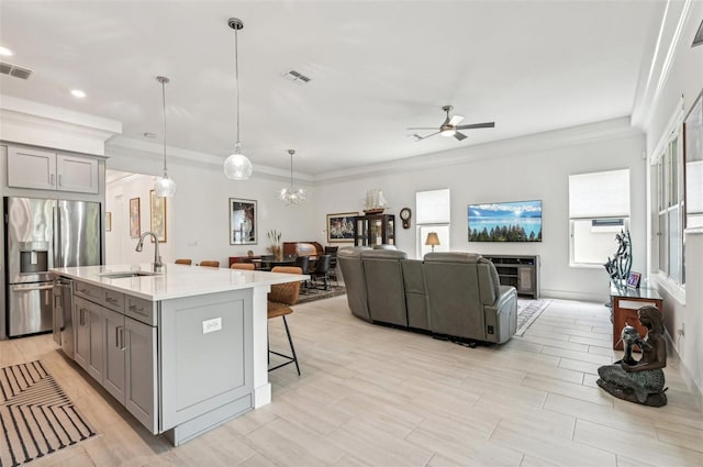 kitchen with pendant lighting, sink, ceiling fan with notable chandelier, a fireplace, and stainless steel appliances