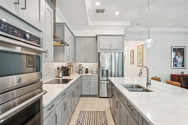 kitchen featuring decorative backsplash, light stone counters, pendant lighting, stainless steel appliances, and sink