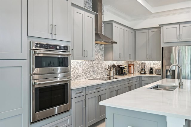 kitchen with backsplash, wall chimney exhaust hood, light stone countertops, stainless steel appliances, and sink