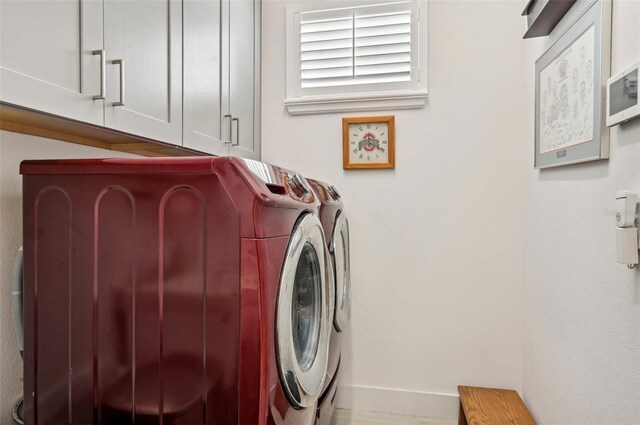 clothes washing area with cabinets and washing machine and dryer