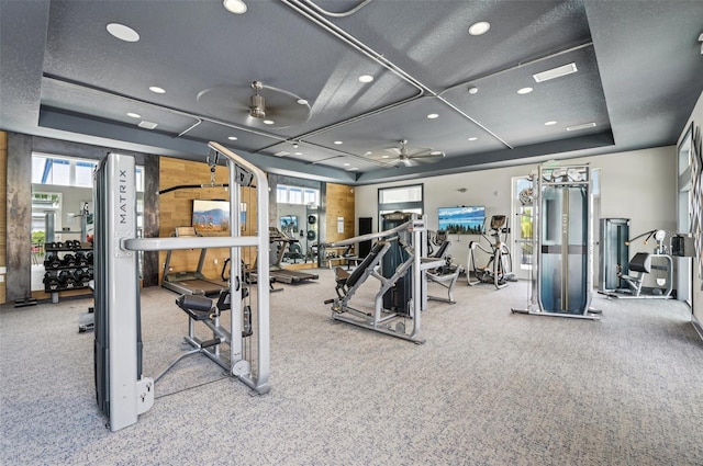 exercise room with a textured ceiling, a raised ceiling, ceiling fan, and carpet floors