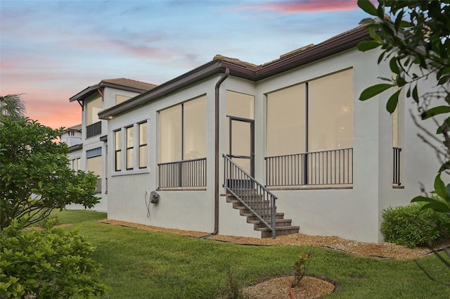 property exterior at dusk featuring a yard