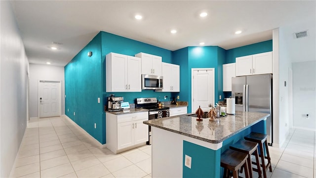 kitchen with white cabinetry, visible vents, a breakfast bar, appliances with stainless steel finishes, and a sink
