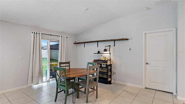 dining space with light tile patterned floors, baseboards, and lofted ceiling
