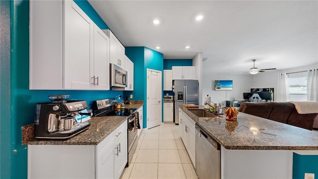 kitchen with a sink, appliances with stainless steel finishes, an island with sink, white cabinetry, and light tile patterned flooring