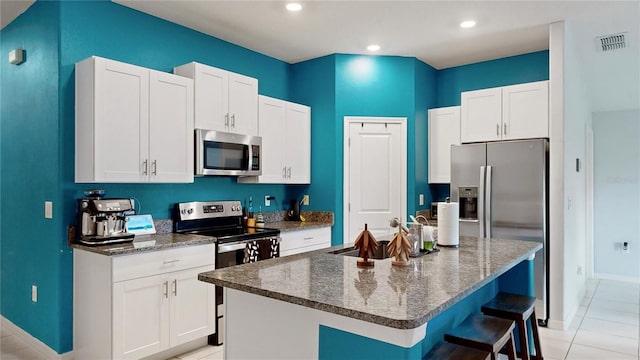 kitchen featuring white cabinets, sink, stainless steel appliances, and an island with sink