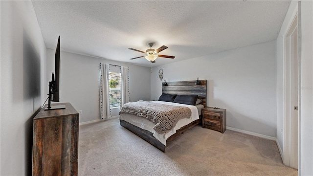 bedroom featuring ceiling fan, a textured ceiling, light colored carpet, and baseboards