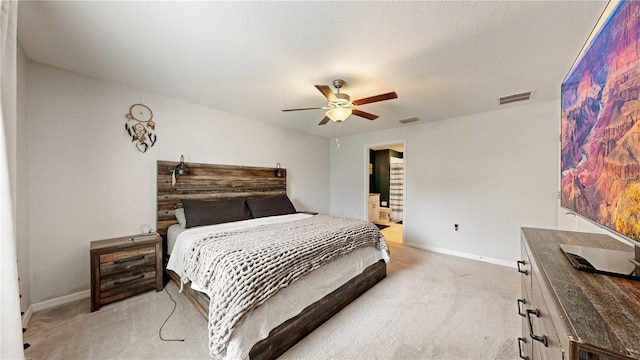 bedroom featuring light colored carpet, ceiling fan, and ensuite bathroom