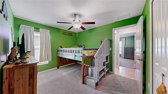 tiled bedroom with visible vents, baseboards, ceiling fan, a textured ceiling, and carpet floors