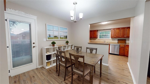 dining area with a textured ceiling, a chandelier, light hardwood / wood-style floors, and sink