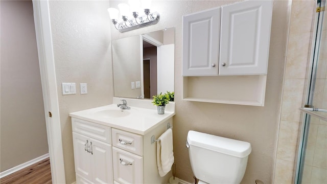 bathroom featuring wood-type flooring, vanity, a shower with shower door, and toilet