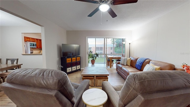 living room with light wood-type flooring, a textured ceiling, and ceiling fan