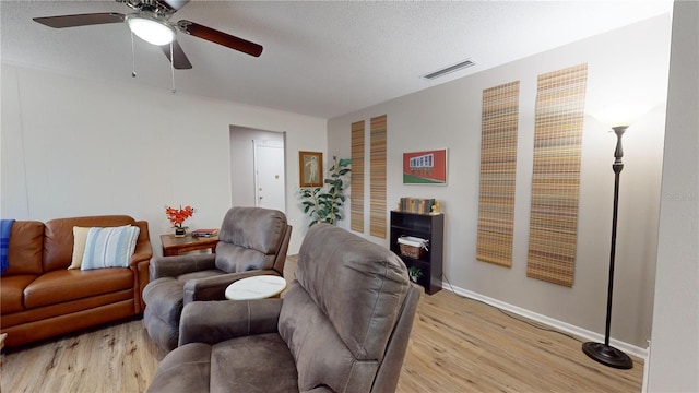 living room featuring ceiling fan, a textured ceiling, and light wood-type flooring