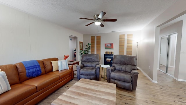 living room featuring ceiling fan, a textured ceiling, and light hardwood / wood-style floors