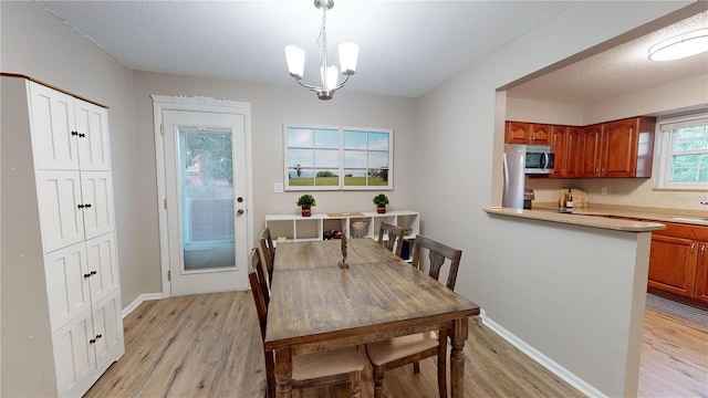 dining room featuring a notable chandelier, light wood-type flooring, and a textured ceiling