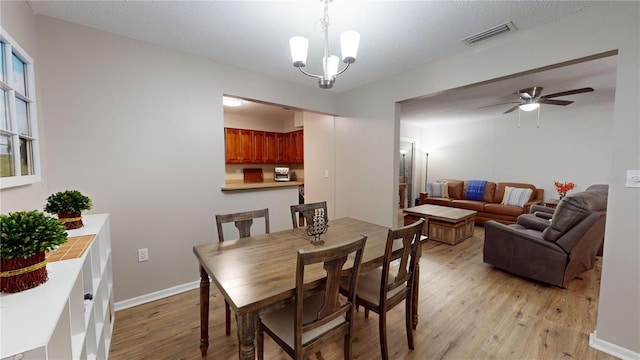 dining area featuring a textured ceiling, ceiling fan with notable chandelier, and light hardwood / wood-style flooring