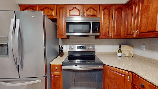 kitchen featuring stainless steel appliances, light stone counters, and backsplash