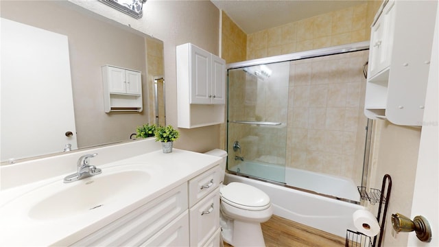 full bathroom featuring combined bath / shower with glass door, vanity, toilet, and hardwood / wood-style flooring