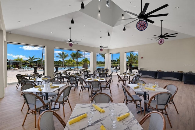 dining space featuring ceiling fan, light hardwood / wood-style floors, and high vaulted ceiling