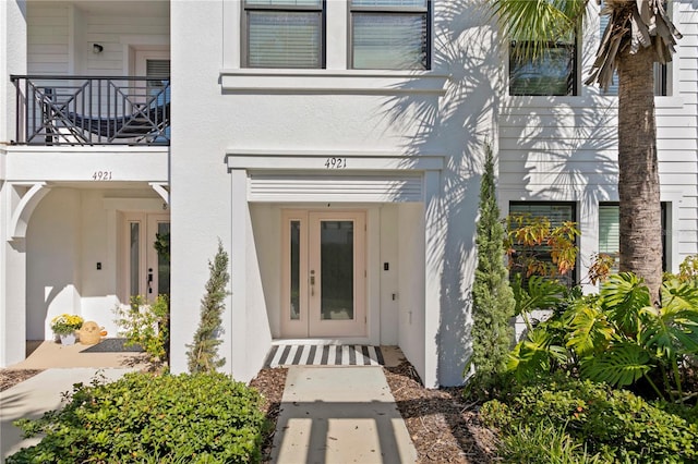 view of exterior entry featuring french doors and a balcony