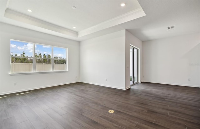 empty room with a tray ceiling, crown molding, and dark hardwood / wood-style flooring