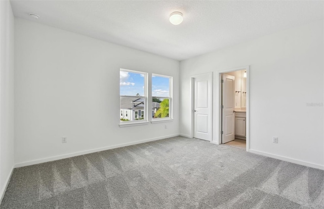 unfurnished bedroom with ensuite bathroom and light colored carpet