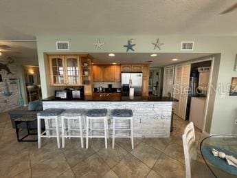 kitchen featuring ceiling fan, a kitchen bar, stainless steel fridge with ice dispenser, and tile patterned floors