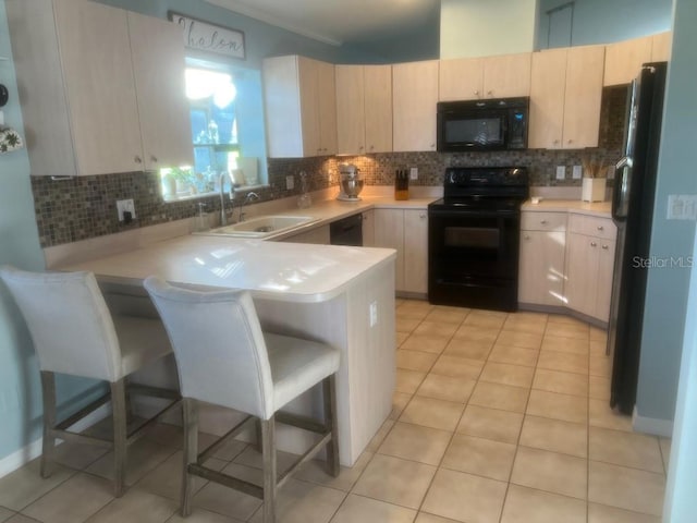 kitchen featuring a kitchen breakfast bar, black appliances, kitchen peninsula, and backsplash