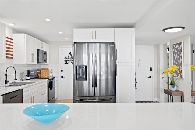 kitchen with light stone counters, black appliances, white cabinetry, and sink