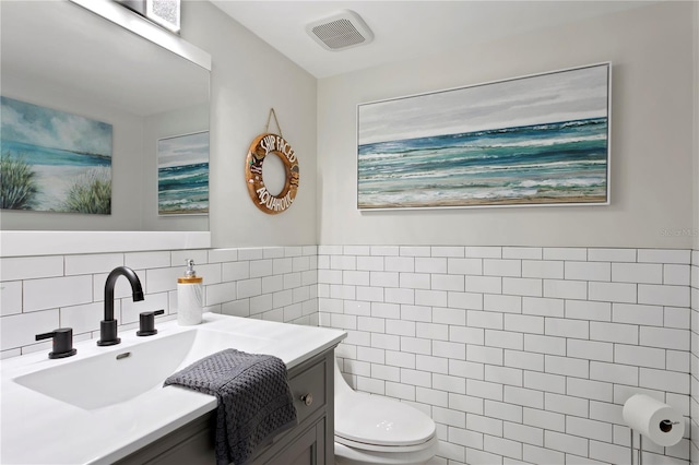 bathroom featuring tile walls, vanity, and toilet