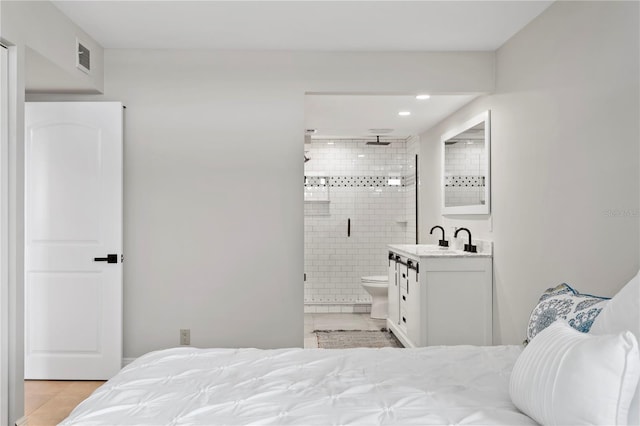 tiled bedroom featuring connected bathroom and sink