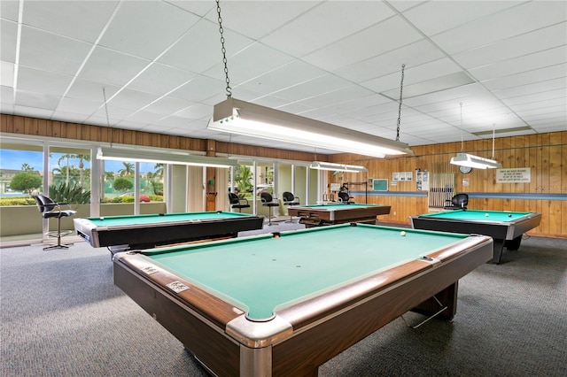 game room with a paneled ceiling, wood walls, carpet, and billiards