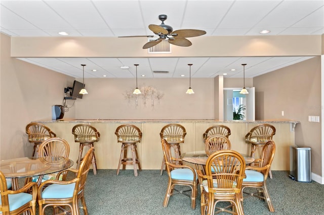 bar featuring a drop ceiling, hanging light fixtures, carpet flooring, and ceiling fan